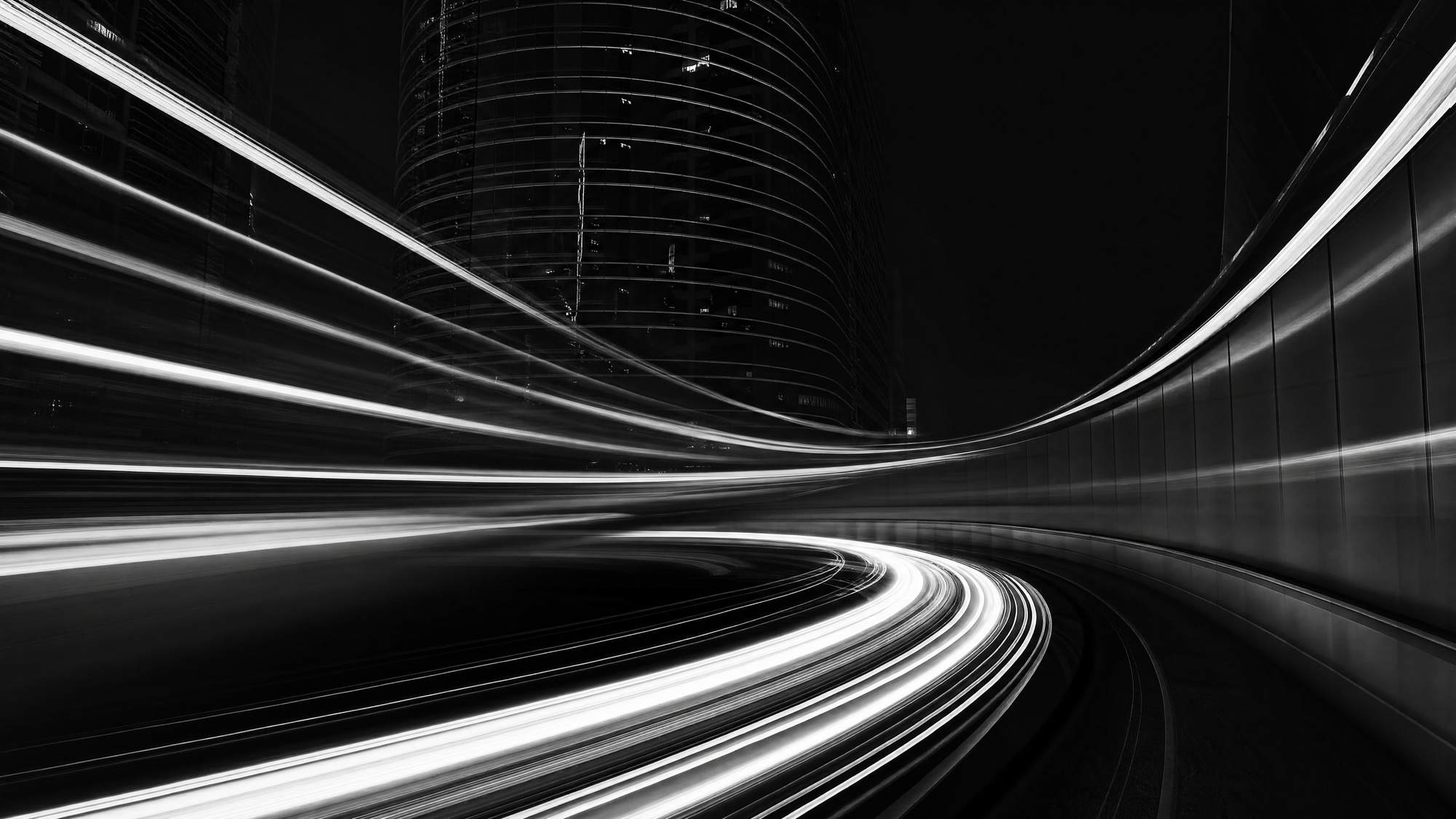 Light trails of night traffic curving past a tower — investment in motion